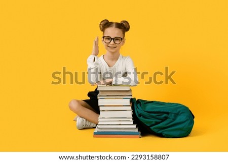 Back To School. Nerdy Little Schoolgirl Sitting With Books And Raising Hand, Smart Clever Preteen Female Pupil Has Answer To Question, Enjoying Study, Posing Isolated On Yellow Background, Copy Space