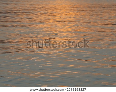 Very beautiful reflection in the water of the rays of the sunset. Ripples on the water. Close-up