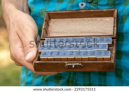 Man holding an old fashioned retro wooden box full of movable type rubber stamp alphabet letters Classic font letter set closeup print writing and literacy, language and communication abstract concept