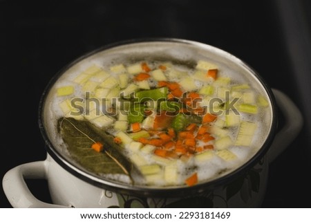 Close up shot of making soup in the retro sauce pan. Boiling hot soup with steam coming out. Soup cooking process