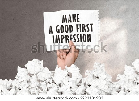 Hand holds a piece of paper with text MAKE A GOOD FIRST IMPRESSION on a gray wall background