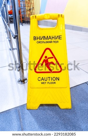 Caution Wet Floor yellow warning sign on a tile floor in a superstore