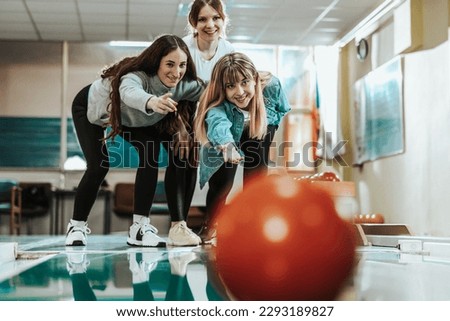Three cheerful young woman having fun while bowling and speding time together.