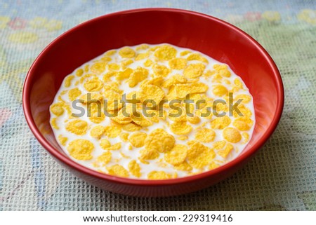 Red cup with cornflakes on the tablecloth