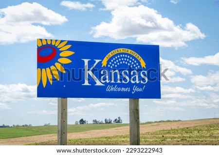 Kansas welcomes you - welcome roadside sign with a popular Latin phrase ad astra per aspera (through hardships to the stars), driving and travel concept