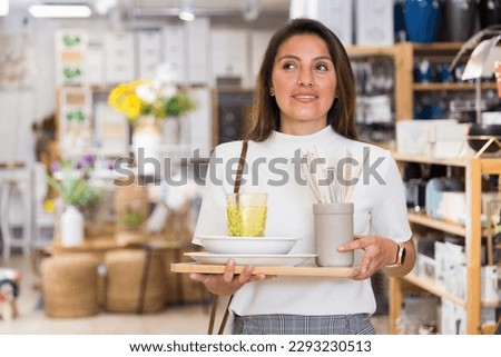 Positive hispanic female customer looking for tableware in home decor store