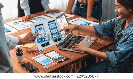 Panorama shot of front-end developer team brainstorming UI and UX designs for mobile app on paper wireframe interface. User interface development team planning for user-friendly UI design. Scrutinize Royalty-Free Stock Photo #2293235877