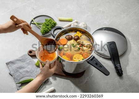 The scene of using a pressure cooker to make soup and cook dishes in the kitchen, marble countertop background, wood grain desktop. Royalty-Free Stock Photo #2293260369