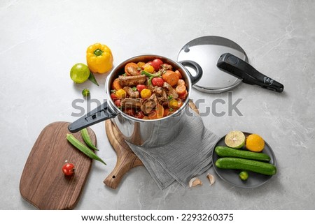 The scene of using a pressure cooker to make soup and cook dishes in the kitchen, marble countertop background, wood grain desktop. Royalty-Free Stock Photo #2293260375