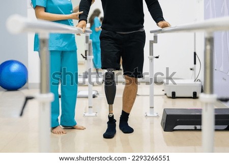Physiotherapist helping patient with prosthetic leg at parallel bars Royalty-Free Stock Photo #2293266551