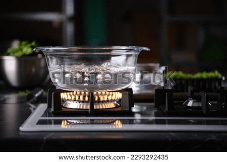Water boiling in transparent glass pot on gas stove
