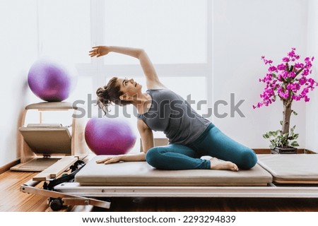 latin woman doing pilates exercises on reformer bed at home in Mexico, hispanic people Royalty-Free Stock Photo #2293294839