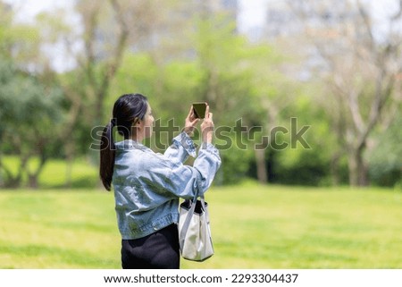 Woman use cellphone to take photo in the garden