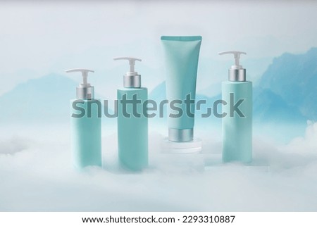 Set of cosmetic container with pump dispenser bottles and tube in light blue color placed on transparent podium. Natural background with mountains behind and white smoke