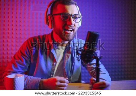 A video blogger records content in his studio. The host of the video blog is a young man who is very enthusiastic about telling his subscribers a story