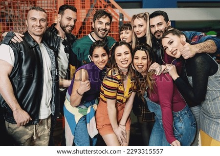 Youthful Friends Posing at Arcade - A diverse group of friends in an arcade, smiling at the camera. One Asian woman among Caucasian friends. Royalty-Free Stock Photo #2293315557