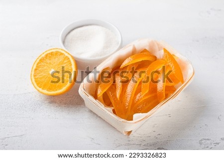 Wicker birch basket with fresh juicy candied oranges with fresh juicy orange and sugar on a light gray background Royalty-Free Stock Photo #2293326823