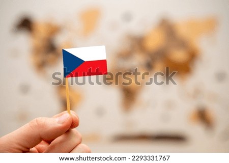 Czech Republic flag in mans hand on the wooden world map background. Global economy and geopolitics concept. 