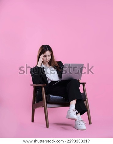 full body image of asian businesswoman using laptop on pink background