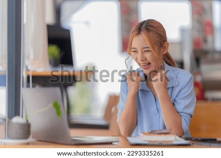 happy young businesswoman Asian siting on the chairs cheerful demeanor raise holding coffee cup smiling looking laptop screen. Making opportunities female working successful in the office.