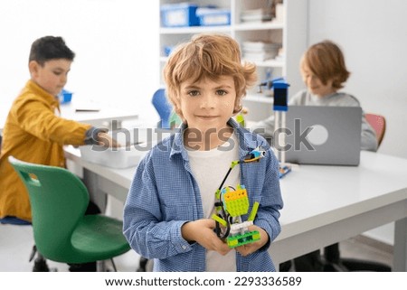 Robotics programming class. Children construct and code Robot. STEM education using constructor blocks and laptop, remote control joystick. Technology educational development for school kids. Royalty-Free Stock Photo #2293336589