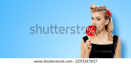 Tasty discounts, rebates, deals, sales concept. Beautiful woman licking red signboard % percent sign, wear pinup black dress, isolated orange yellow background. Pin up girl. Wide banner. huge