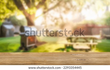 summer time in backyard garden with grill BBQ, wooden table, blurred background Royalty-Free Stock Photo #2293354445