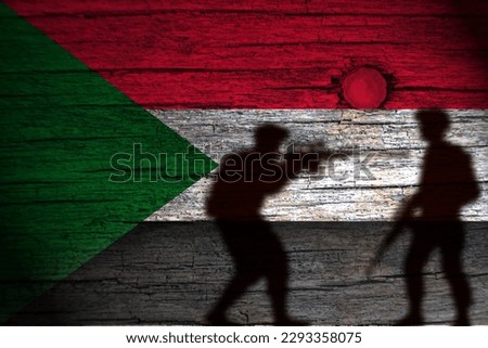 painting of the sudan flag on wood and the shadow of its soldiers. Royalty-Free Stock Photo #2293358075