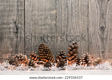 Holiday decoration with Christmas lights and cones over wooden background Royalty-Free Stock Photo #229336537