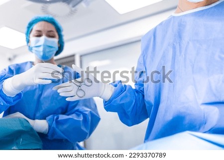 Low Angle Shot in the Operating Room, Assistant Hands out Instruments to Surgeons During Operation. Surgeons Perform Operation. Professional Medical Doctors Performing Surgery.