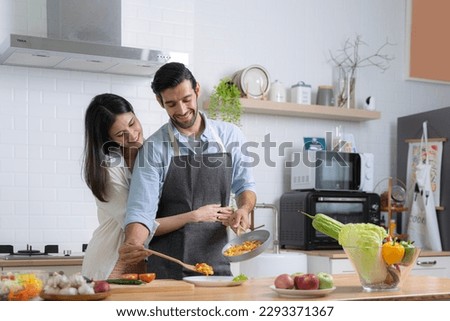 Photos of two passionate people. Tender couple prepares Valentine's Day. Dishes. Nutrition. Woman embraces man who is cooking macaroni. Romance in the kitchen of the house
