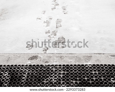 rubber, door mat and footprints on freshly fallen snow in front of porch of residential building Royalty-Free Stock Photo #2293373283