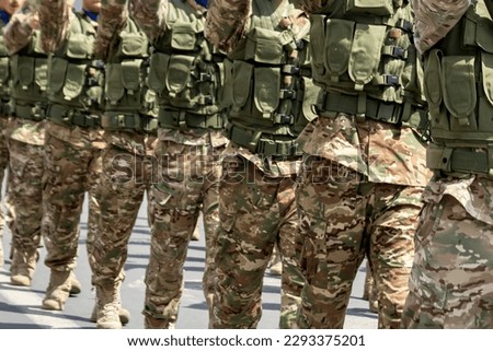 Close-up of marching soldiers in military camouflage uniform, front view