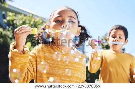 Boy, girl and playing with bubbles outdoor in garden, backyard or park with happiness, family or siblings. Children, soap bubble game and playful in childhood, youth and summer sunshine on holiday