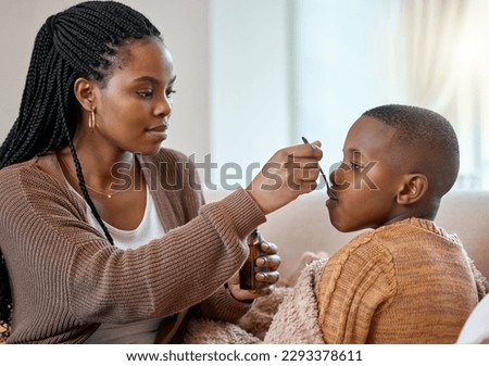 This will make you feel better. a young mother giving her sick son cough syrup at home. Royalty-Free Stock Photo #2293378611
