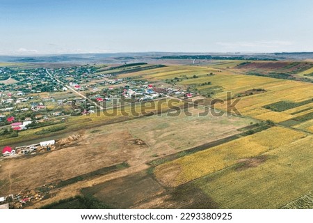 Picturesque landscape of a rural village with vast agriculture fields, adorned with yellow patches of wheat. The scenic beauty of the European countryside is on full display