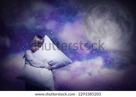 Boy sleepwalker hugging pillow in clouds in starry sky with full moon