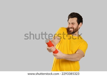 Emotional man with party popper on light grey background. Space for text