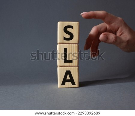 SLA - Service Level Agreement. Wooden cubes with word SLA. Businessman hand. Beautiful grey background. Business and Service Level Agreement concept. Copy space.