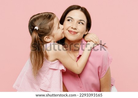 Happy fun adorable lovely woman wearing casual clothes with child kid girl 6-7 years old. Daughter kissing mother cheek, look aside isolated on plain pastel pink background. Family parent day concept Royalty-Free Stock Photo #2293393165