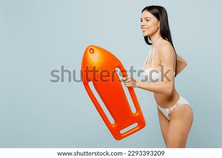 Side view young fun lifeguard woman wear swimsuit near hotel pool hold in hand lifebuoy run fast hurry up isolated on plain pastel light blue cyan background. Summer vacation sea rest sun tan concept Royalty-Free Stock Photo #2293393209