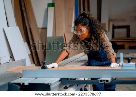 Professional carpenter woman check about cutting machine during work with wood product in workplace.