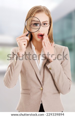 Young smiling business woman looking into a magnifying glass.