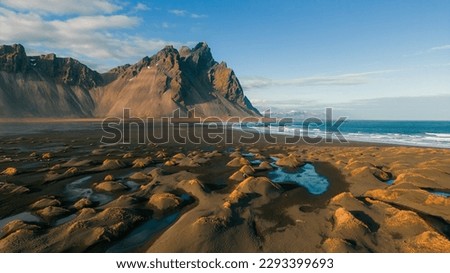 Famous Vestrahorn mountain in Stokksnes, Iceland. Sunrise on beach full of tufts of grass. One of the best and famous travel destinations.  Wallpaper background of the wild icelandic nature.
