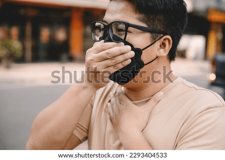 Asian young man wearing face mask to protect PM 2.5, protect pollution, anti smog and viruses on road in the city. Global warming concept. Healthcare concept. Environmental pollution concept. Royalty-Free Stock Photo #2293404533