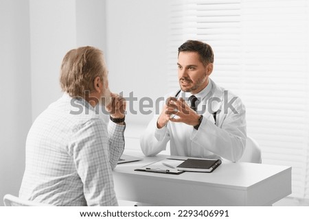 Doctor consulting senior patient at white table in clinic Royalty-Free Stock Photo #2293406991