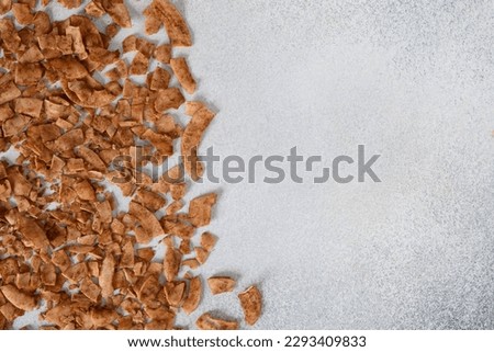 Coconut chips with cinnamon on gray background with copy space. View from above. Royalty-Free Stock Photo #2293409833