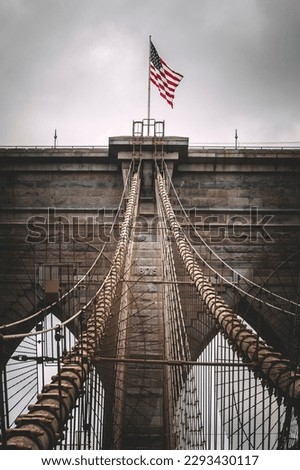 Shot of Brooklyn Bridge in New York, with the American flag waving on top of it