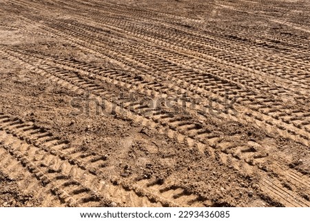Track marks on loose soil after operating a crawler bulldozer. Mining machinery moving clay, smoothing gravel surface. Royalty-Free Stock Photo #2293436085