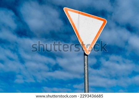 International traffic sign 'Yield sign' or 'Give way'. Blue sky with some clouds is on background.